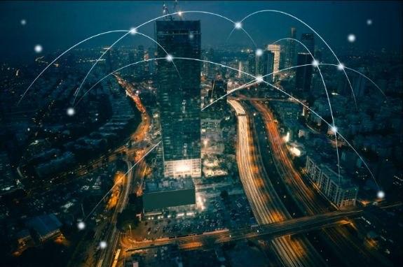 Aerial night view of a city overlaid with a connected communications network